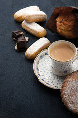 Coffee with different sweets on the dark table vertical
