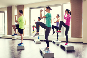 group of people working out with steppers in gym