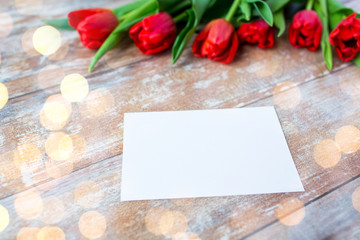 close up of red tulips and blank paper or letter