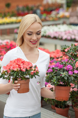 Cute blond lady is choosing plant in shop