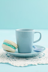 Cup of coffe with a turquoise macaron with buttercream filling