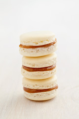 Three white macarons with caramel filling piled up
