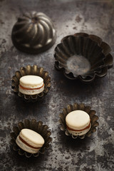 White macarons with caramel and chocolate filling on dark background