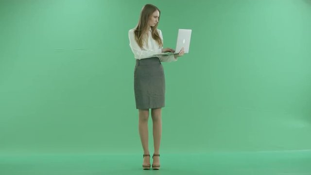 Business woman typing on laptop on green screen