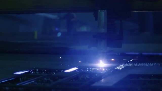 Close-up footage of a CNC plasma cutter that is cutting out metal objects in a heavy industry factory. Shot on RED Cinema Camera.