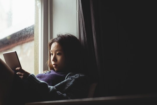 Brunette sitting on the edge of the window using tablet