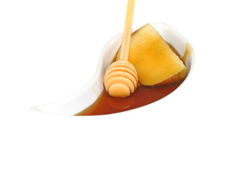 Pouring honey on a slice of apple with a honey dripper. A snack eaten by jews in the holiday of Rosh Hashana