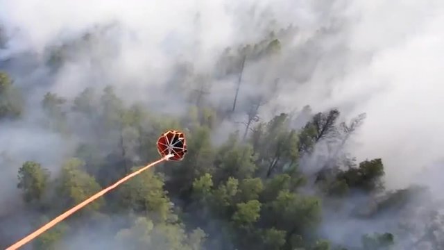 POV from a water dropping helicopter of the bucket.