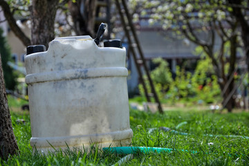 Water tank for watering the grass. Container to retain rainwater in the garden. White plastic jerrycan. Gallon water reserve