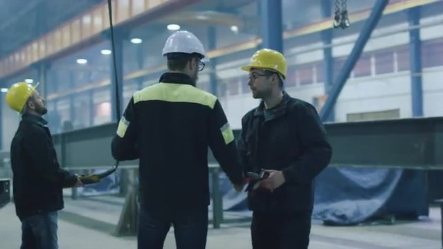 Engineer in hardhat is greeting workers with a handshake at a heavy industry factory. Shot on RED Cinema Camera.