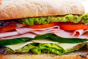 Sandwich with lettuce, tomatoes, cucumber, red onion, salami, ham, cheese