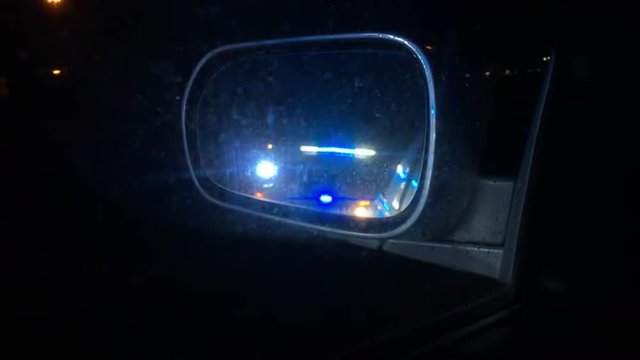 Pulled over by police officer whose lights are flashing in the side view mirror.