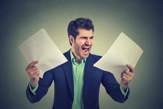 Angry stressed screaming business man with documents papers paperwork