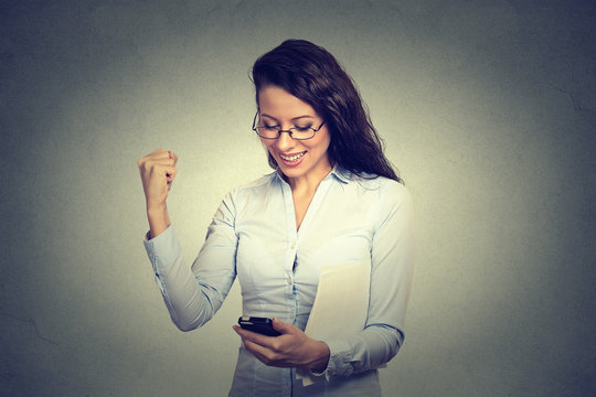 Happy woman looking at mobile phone smiling pumping fist celebrates success