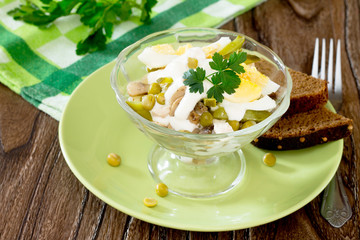 Salad with chicken and green peas on a wooden table, rustic styl