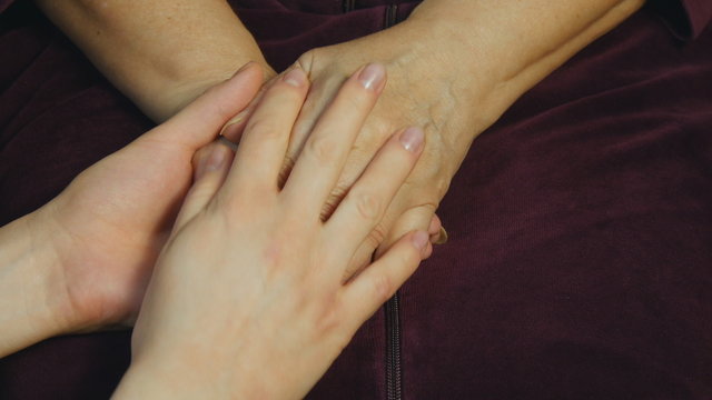 A young hand comforting an elderly pair of hands. 