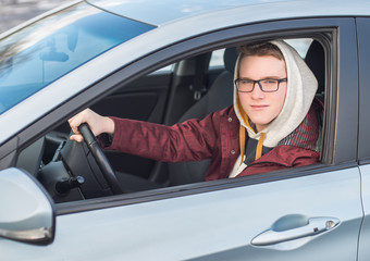 Naklejka premium Young man in glasses driving a car.