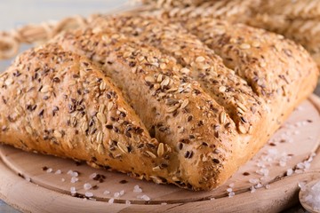 Loaf of cereal bread on wooden board with salt around © yommy