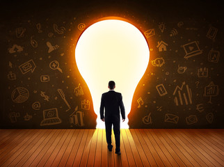 Obraz premium Business man looking at bright light bulb in the wall