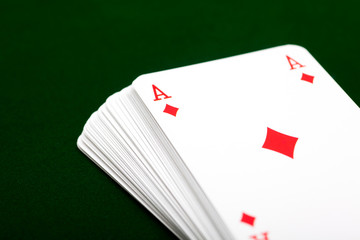 Deck of cards with ace of diamond card in top on green background