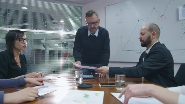 Employee is making a presentation for a team of colleagues that are sitting in a meeting room. Shot on RED Cinema Camera.