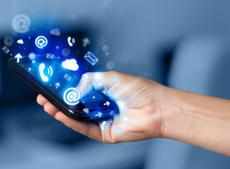 Business man holding smart phone with media icons