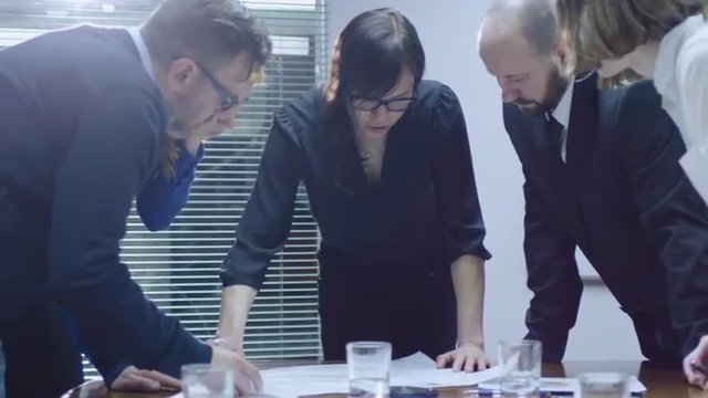 Female employee is making a presentation for a team of colleagues that are sitting in a meeting room. Shot on RED Cinema Camera.