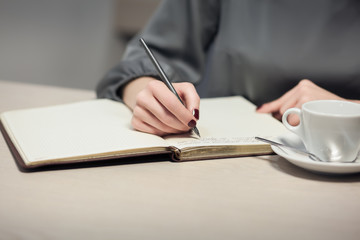 female has coffee break and writing notes in diary or notepad;