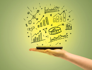 Obraz premium Sales charts on top of mobile phone in hand