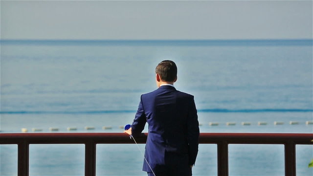 Stylish groom enjoying beautiful seascape and clear blue sky in  Montenegro, Budva