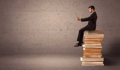 Businessman with tablet sitting on books