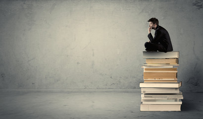 Student sitting on stack of books