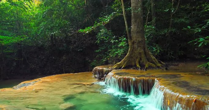 Small calm river with waterfall cascade flows through wild tropical rainforest