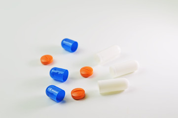 Blue and white capsules and orange tablets