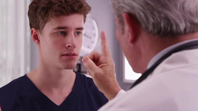 Portrait of young Caucasian sports athlete having eyesight checked by doctor