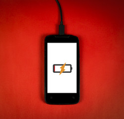 Smart phone is charging on red background, vignette added