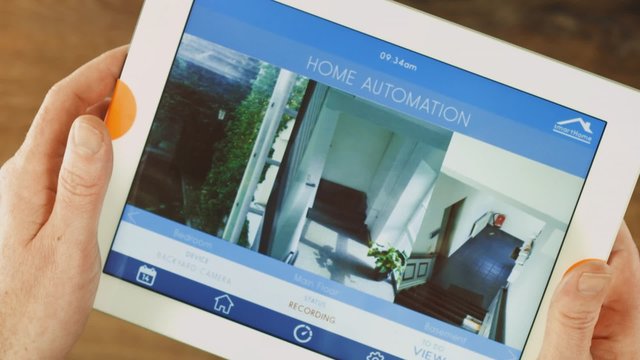 Smart house automation application on tablet controlling the House / Building. above shot on stylish home office wooden desktop.