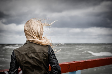 Blond girl looking on the stormy ocean