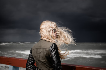 Blond girl looking at the stormy ocean