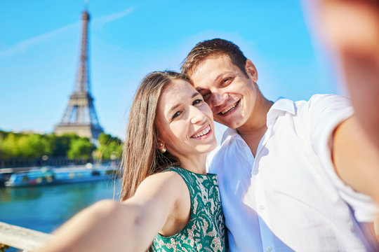 Couple having a date and taking selfie near the Eiffel tower in Paris, France