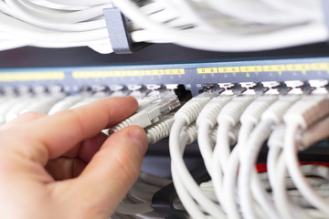 IT consultant connects a network cable into switch in datacenter