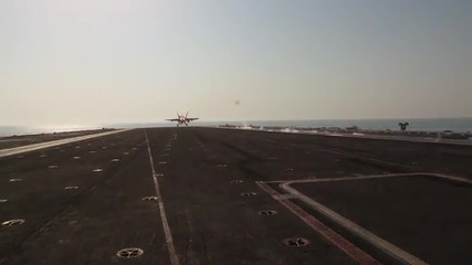 Various jet aircraft take off from the deck of an aircraft carrier.
