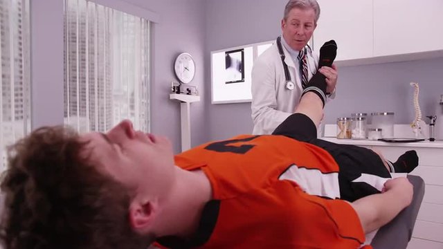 Mid-aged physical therapist examining college athlete sports injury