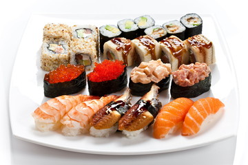  Sushi rolls assortment on a white plate. Different kinds of sushi side view. Big and mouthwatering sushi set  