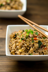 Basil chicken fried rice with chopsticks on a wooden background viewed from above. This thai inspired meal is perfect for a quick lunch or served as side dish.