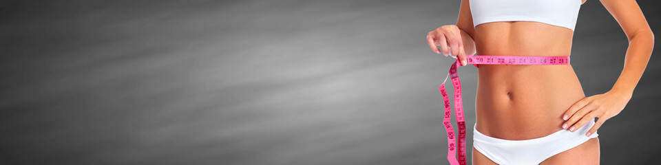 Woman waist with measuring tape over gray background.