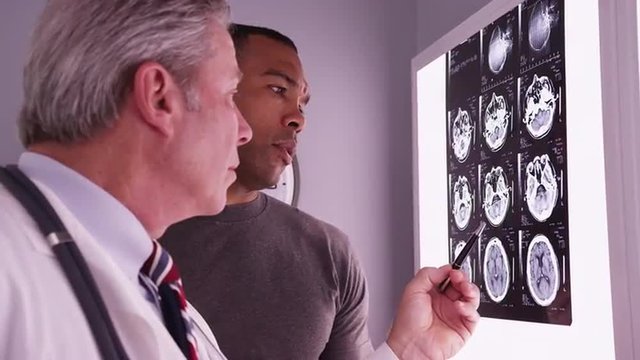 Male black patient looking at brain xrays with radiologist