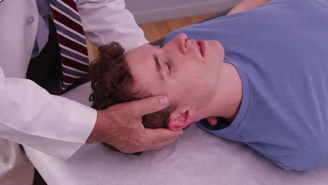 Young adult male having neck injury examined by chiropractor