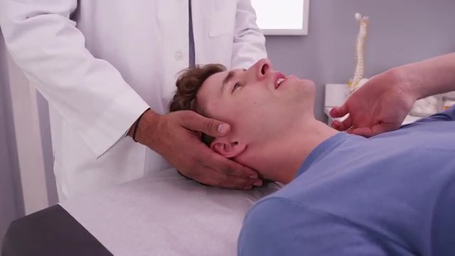 Young Caucasian male having neck examined by African chiropractor