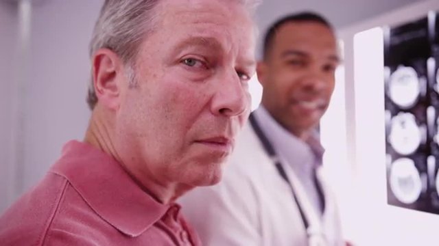 Senior male patient looking at camera with young medical practitioner